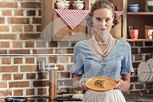 attractive adult housewife with freshly baked cake looking at camera
