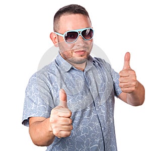 Attractive adult man with beard wearing sunglasses in summer shirt shows thumb up gesture isolated on white background