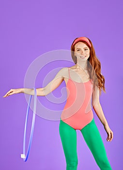 Attractive aerobics trainer rotating hula hoop on hand, doing exercises for biceps