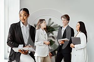 Attractive african american female director CEO sitting at the office table with group of colleagues on the background