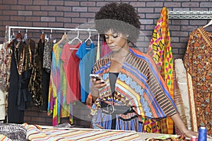 Attractive African American female fashion designer using cell phone