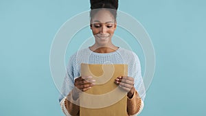 Attractive african american girl opening envelope with exams results on camera over colorful background