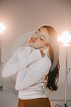 attractive african american girl in white turtle neck posing with closed eyes in studio