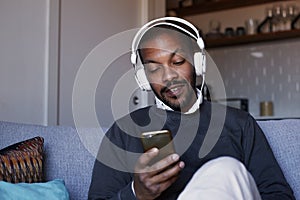 Attractive African American man with white headphones listening to music on his phone. Concept of relaxation.