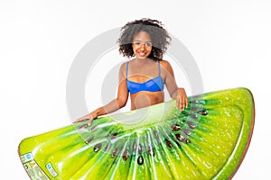 Attractive african girl in a blue separate bathing suit holds a kiwi swimming mattress on a white background