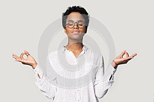 Attractive african woman doing meditation pose isolated on grey background