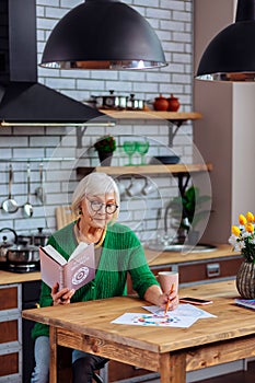 Attractive aged female considering vedic tables sitting at kitchen table