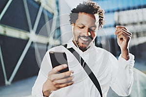 Attractive american african black man listening to music with headphones in urban background. Happy men using smartphone