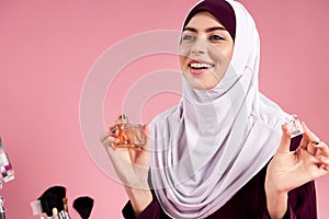 Attractive Arabian woman in hijab uses perfume