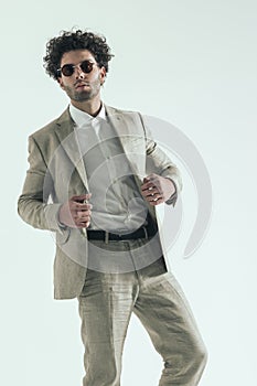 Attractive arabic young man with curly hair pulling and adjusting suit