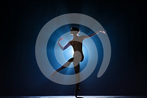 Attractive, artistic, talented young girl, ballerina dancing classical dance, performing against dark blue background