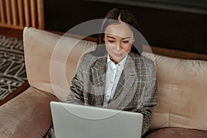 Attractive asian business woman working laptop sitting sitting in a cozy little office