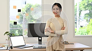 Attractive Asian businesswoman or CEO in casual clothes arms crosses, standing in office