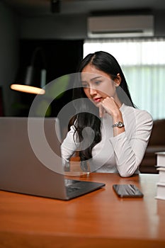 Attractive Asian businesswoman focusing on reading an online information on the website