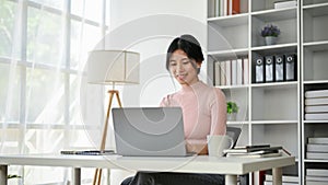 An attractive Asian businesswoman looking at her laptop screen, replying emails