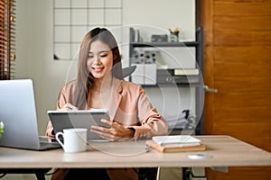 Attractive Asian businesswoman using digital tablet, checking her meeting schedule