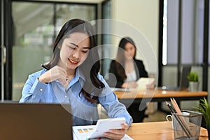 Attractive Asian businesswoman working on her task at her desk in office co-working room