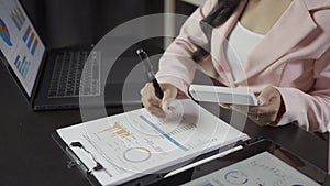 Attractive Asian businesswoman working with laptop and checking financial documents and analyzing company