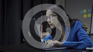 Attractive Asian businesswoman working with laptop and checking financial documents and analyzing company