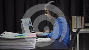 Attractive Asian businesswoman working with laptop and checking financial documents and analyzing company