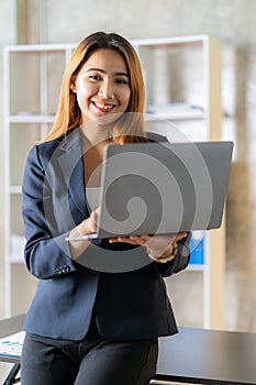 Attractive Asian female business owner in apron with open door sign vertical image