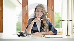 An attractive Asian female lawyer or attorney sits at her office desk