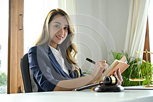 Attractive Asian female lawyer sits at her office desk in modern office room