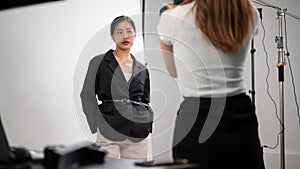 Attractive Asian female model is posing for a photographer, working in a fashion photoshoot studio