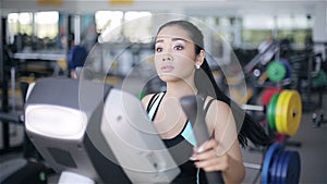 Attractive asian girl at the gym exercising on the xtrainer machine