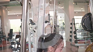 Attractive Asian girl in sportswear lifting up barbell at the fitness sport gym. Side view portrait of athletic people lifestyles