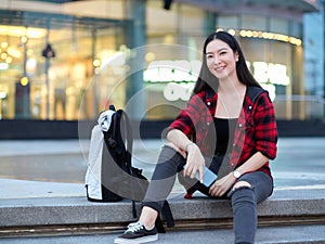 Attractive asian hipster young woman solo traveller with backpack sitting on stairs