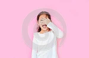 Attractive asian little kid girl peeking in shock covering face and eyes by hand. Child looking through his fingers isolated on