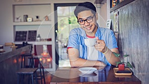 Attractive Asian man drinking coffee at the table in coffee shop. Film tone effected