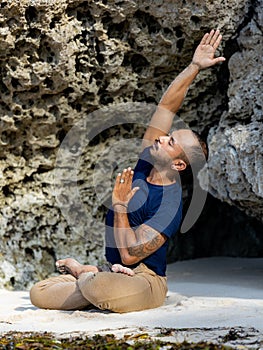 Attractive Asian man sitting in Lotus pose. Padmasana. Side extension. Closed eyes. Side tilt. Yoga retreat. Healthy lifestyle.