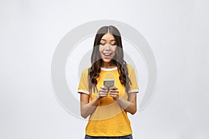 Attractive Asian teenage girl looking at her mobile phone screen with joyful face, on white background for copy space.