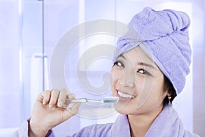 Attractive asian woman brushing teeth