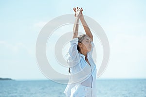 attractive asian woman with closed eyes standing with wide arms in front of