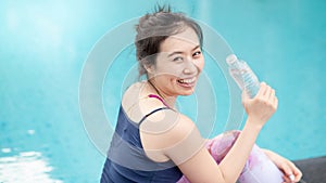 Atractivo asiático una mujer bebiendo Agua sobre el nadar piscina 