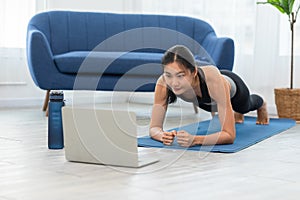 Attractive Asian woman looking laptop practice yoga plank online course at home to meditation comfortable and relax,Health care