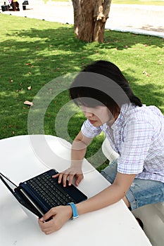 Attractive Asian woman is outdoors with laptop