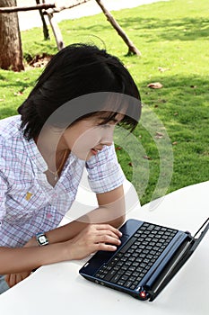 Attractive Asian woman is outdoors with laptop