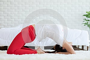 Attractive Asian woman practice yoga Light thunderbolt pose or Laghu Vajrasana pose to meditation in bedroom