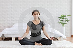 Attractive Asian woman practice yoga lotus pose to meditation on bed after wake up