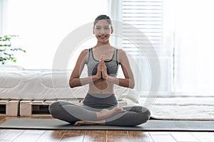 Attractive Asian woman practice yoga lotus pose to meditation in bedroom