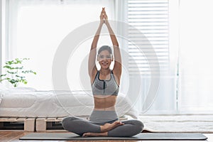 Attractive Asian woman practice yoga lotus pose to meditation in bedroom