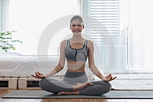 Attractive Asian woman practice yoga lotus pose to meditation in bedroom