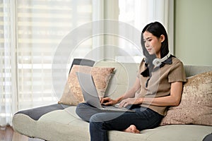 Attractive Asian woman remote working from home, using laptop computer