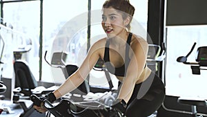 Attractive Asian woman riding on the spinning bike at the gym