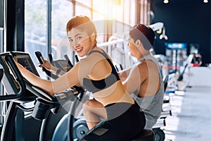 Attractive Asian woman riding on the spinning bike at the gym and looking at camera. Healthy and weight loss lifestyle