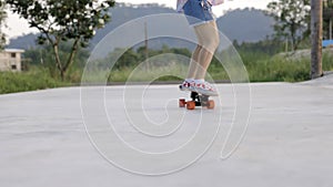 Attractive Asian woman with safety skateboarding knee pad skating at skateboard park .